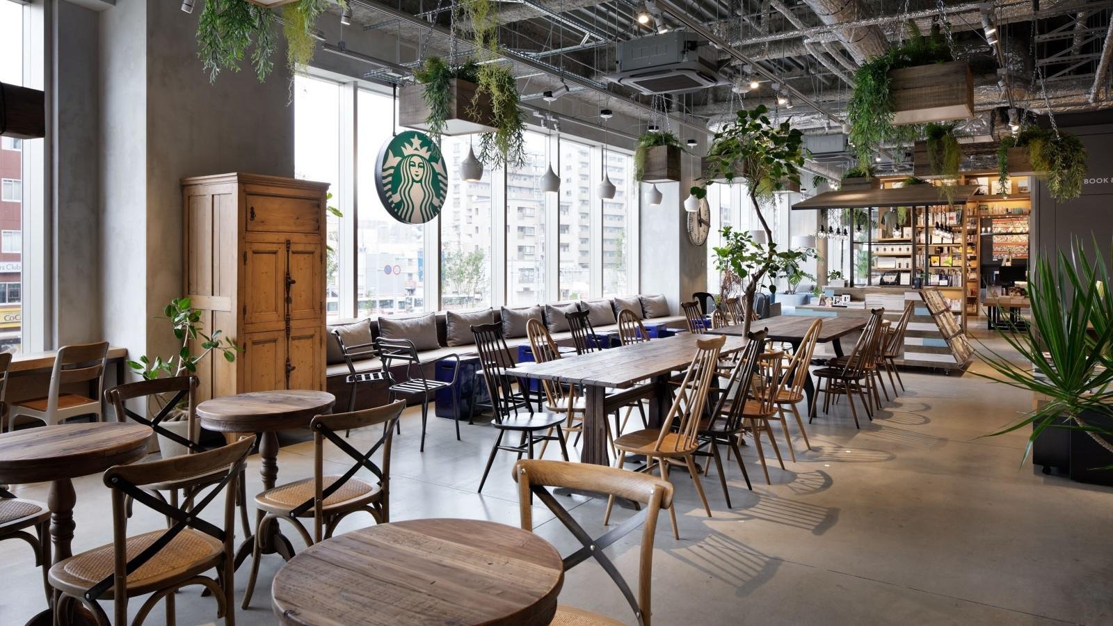 日差しが降り注ぐ、緑と温かみのあるアンティーク家具に囲まれたカフェ席